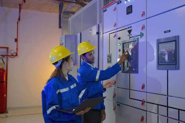 Maintenance engineers are checking electronic system at basement building. Blue collar worker and engineer.